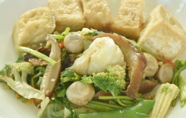 Kızarmış lahana brokolisini yeşil bezelye ve saman mantarı ile karıştır. Tabakta soya soslu vejetaryen yemeği olan çift zarlı tofu.  