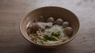 Kaynamış beyaz vermicelli şehriye, yumuşak dilimlenmiş domuz eti ve yemek çubuklarıyla karıştırılmış kase üzerinde top.