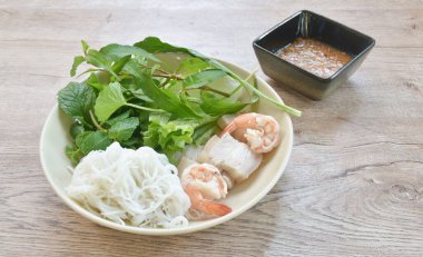 Haşlanmış karidesli erişte ve domuz eti. Tabakta çeşitli sebze salatası sosu.