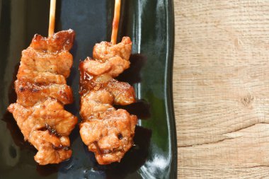 Kızarmış tavuk soslu Japon teriyaki sosu tabağa tahta sopa saplıyor.