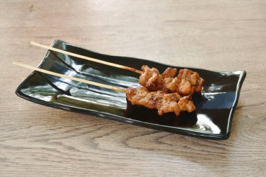 Kızarmış tavuk soslu Japon teriyaki sosu tabağa tahta sopa saplıyor.