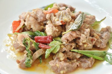 Baharatlı kızarmış biftek, fesleğen yaprağı ve tabakta kuru biber. 