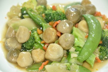 Kızarmış brokoli, yeşil bezelye ve saman mantarlı vejetaryen yemeği tabakta karıştır.  