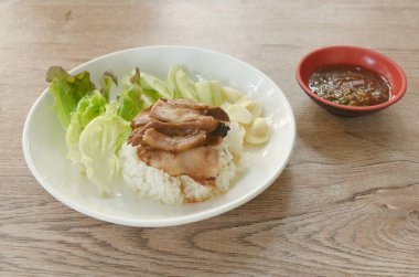 Dilimlenmiş domuz budu, salatalık ve baharatlı biber soslu pilav.