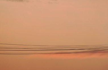 Akşamları turuncu alacakaranlık arka planında elektrik kablosu