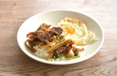 Baharatlı kızarmış bambu filizi ve pirinçli yumurta üzerine fesleğen yaprağı soslu biftek eti.  