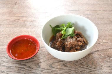 Ağır ateşte pişirilmiş et güveci üzerine dilimlenmiş kereviz sosu ve acı biber sosu 