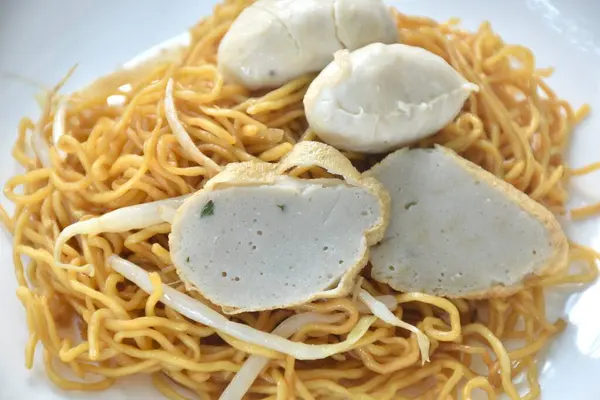 dry Chinese yellow noodles with bean sprout topping pork meatball and slice fish line on plate
