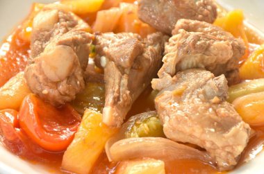 Kızarmış sebze, pirzola, domuz kemiği, tatlı ve ekşi sos, beyaz tabakta. 