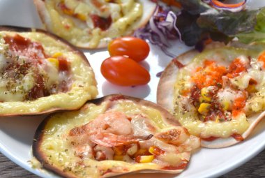 Küçük ev yapımı pizza sosis ve peynir tabakta salata.