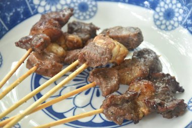 grilled salty beef meat dressings spicy sauce stabbing in wooden stick on plate 