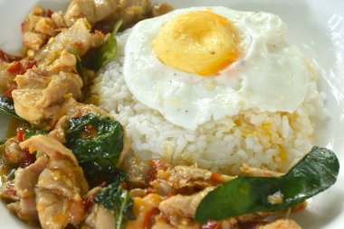 Baharatlı kızarmış tavuk, kuru biber püresi ve pilav üzerine fesleğen, tabakta yumurta.