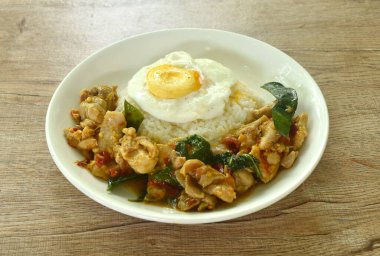 Baharatlı kızarmış tavuk, kuru biber püresi ve pilav üzerine fesleğen, tabakta yumurta.