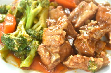 Kızarmış domuz kemiği, buharda pişirilmiş brokoli ve havuç soslu tatlı kırmızı sos.