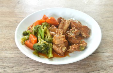 Kızarmış domuz kemiği, buharda pişirilmiş brokoli ve havuç soslu tatlı kırmızı sos.