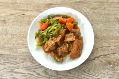 Kızarmış domuz kemiği, buharda pişirilmiş brokoli ve havuç soslu tatlı kırmızı sos.