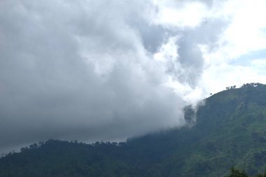 Tayland 'daki Sai Thong su deposunda yağmur bulutu ve sisle kaplı dağ manzarası.