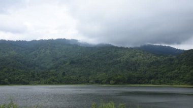 Tayland 'daki Sai Thong su deposunda yağmur bulutu ve sisle kaplı dağ manzarası.