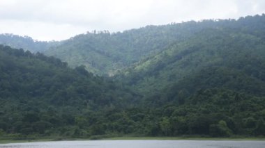 Tayland 'daki Sai Thong su deposunda yağmur bulutu ve sisle kaplı dağ manzarası.