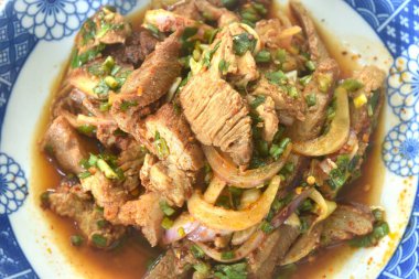 Pirzola ve acılı Tayland salatası dilimlenmiş domuz eti. Tabakta baharatlı ve ekşi.