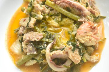 Tavuk ve domuz etli kızarmış deniz ürünleri tabakta sukiyaki soslu yumurta sarısı yiyen sebzeli çift.