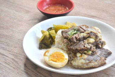 haşlanmış sığır eti yahnisi siyah Çin sebze çorbası haşlanmış yumurta yarısı kesilmiş çift lahana turşusu baharatlı acı biber sosu ve sade pirinç. 