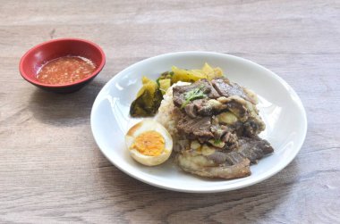 haşlanmış sığır eti yahnisi siyah Çin sebze çorbası haşlanmış yumurta yarısı kesilmiş çift lahana turşusu baharatlı acı biber sosu ve sade pirinç. 