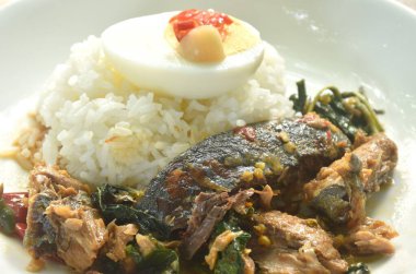 Acı biberli baharatlı kızarmış uskumru ve pirinçli fesleğen haşlanmış yumurta soslu kırmızı sarımsaklı balık sosu tabakta.