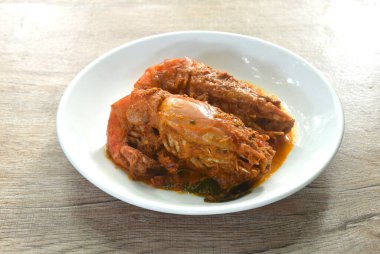 Baharatlı kızarmış nehir karidesi ve dilimlenmiş yeşil yapraklı köri tabağı.  