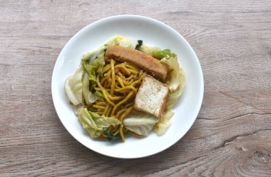 Kızarmış yakisoba şehriyesi ve havuç soslu lahana tabakta vejetaryen yemeği.