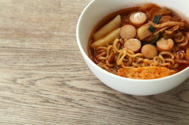 Korean yellow noodles topping slice sausage and cabbage with tofu coupple  tokpokki in kimchi soup in bowl clipart