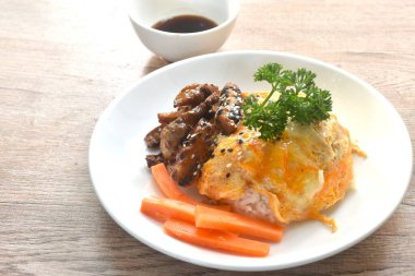 Izgara domuz eti, yumurta ve susamlı soslu teriyaki sosu Japon pilavının üzerine.