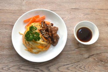 Izgara domuz eti, yumurta ve susamlı soslu teriyaki sosu Japon pilavının üzerine.