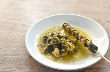 Kiraz ya da altın elma salyangozu pişirmek ahşap sopa saplamak Tayland baharatlı deniz ürünleri sosunu tabakta soslamak