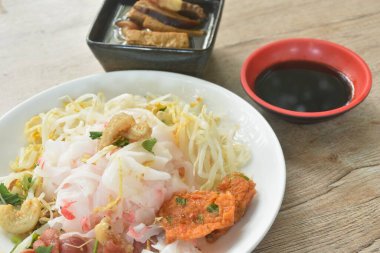 Kızarmış Çin sosisi ve fasulye filizli çıtır domuz göbeği, soya soslu kara soya sosu ve soya fasulyesi sosu ile kaplı buğulanmış büyük pirinç eriştesi.