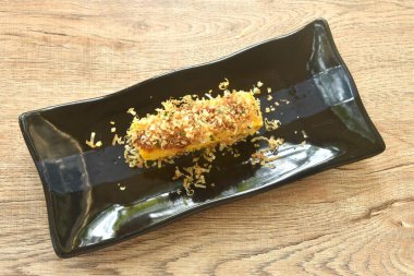 Izgara Tamakoyaki ya da Japon usulü yumurta rulo omleti tabakta kuru balık.