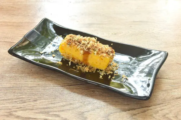 Izgara Tamakoyaki ya da Japon usulü yumurta rulo omleti tabakta kuru balık.