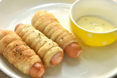 Kızarmış kızarmış roti ekmeği rulo halinde füme tavuk sosisi mayonez sosu tabakta.