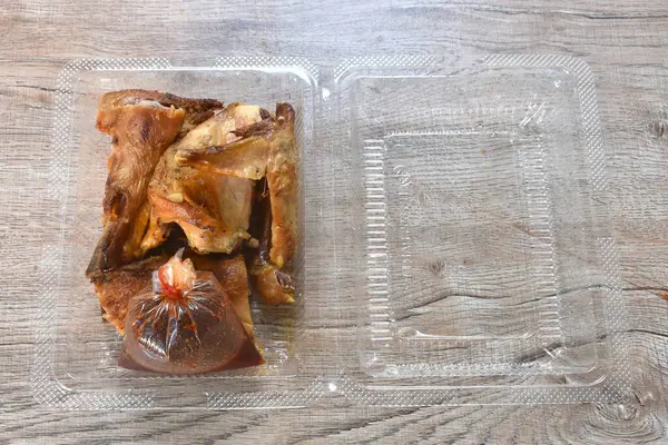 Kızarmış tavuk eti kanadı ve bacağı şeffaf plastik ambalajda baharatlı sosla bandırılmış.
