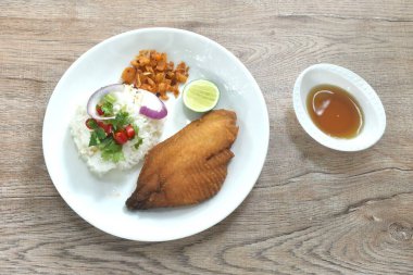 Kızarmış levrek balığı, pilav, kırmızı biber ve arpacık soğanı sosu tabakta.  