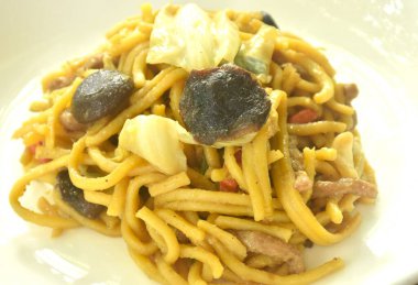 Kızarmış yakisoba Japon eriştesi ve tabağında mantar olan lahana.