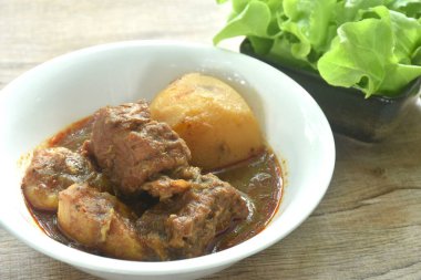 Körili biftek ya da Hint yemeği dilimlenmiş patates ve taze yeşil meşe ile yenir.