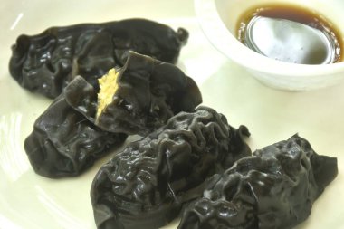 Buharda pişmiş mürekkep balığı Gyoza ya da Japon hamur tatlısı doldurulmuş körili domuz püresi Shoyu sosu tabakta. 