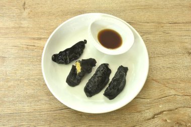 Buharda pişmiş mürekkep balığı Gyoza ya da Japon hamur tatlısı doldurulmuş körili domuz püresi Shoyu sosu tabakta. 