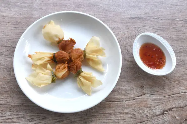 Altın poşet kızarmış hamur hamuru doldurulmuş domuz pirzolası ve karidesli Tayland aperatifi tatlı acı biber sosunu fincana bandırıyor.