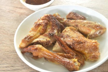 Kızarmış tavuk eti kanadı ve bacağı tabakta tatlı ve baharatlı sosa batırılmış.