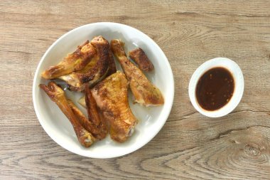 Kızarmış tavuk eti kanadı ve bacağı tabakta tatlı ve baharatlı sosa batırılmış.