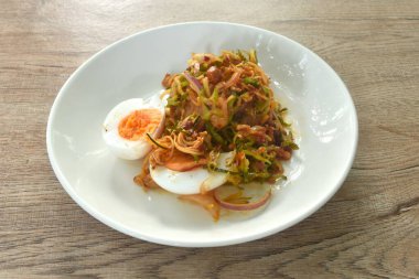 Baharatlı ve ekşi fasulyeli fasulye ve muz çiçekli domuz soslu haşlanmış yumurtalı Tayland salatası.