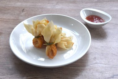 Altın poşet kızarmış hamur hamuru doldurulmuş domuz pirzolası ve karidesli Tayland aperatifi tatlı acı biber sosunu fincana bandırıyor.