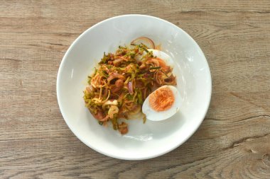 Baharatlı ve ekşi fasulyeli fasulye ve muz çiçekli domuz soslu haşlanmış yumurtalı Tayland salatası.